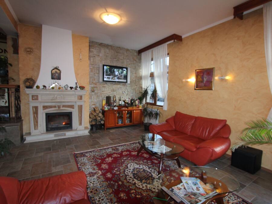 A living room with a fireplace, red leather sofa, and a coffee table.