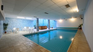En indendørs swimmingpool med fliserede vægge og trægulv.