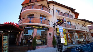 En bygning med flere etager, hvor der er en restaurant kaldet 'Veranda BBQ & Wine' i stueetagen.