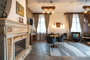 Una sala de estar con chimenea, un comedor con sillas, una mesa y vistas al exterior a través de amplios ventanales.