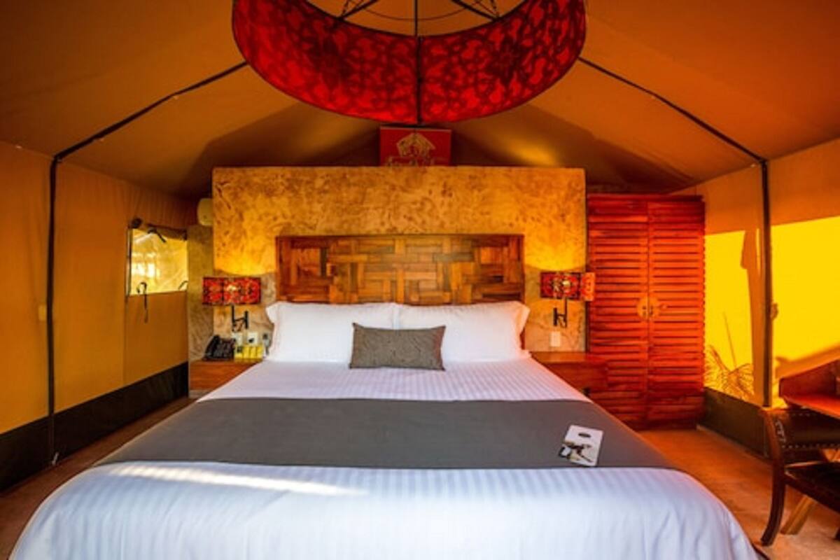 Una cama grande con cabecera, un farol rojo y un mueble de madera.