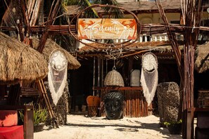 A rustic beach hut with a sign reading "Serenity Beach Club."