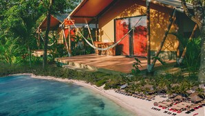 A beachfront property with a wooden deck, a hammock, and a pool. - Serenity Authentic Glamping Tulum (Xpu-Ha)