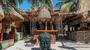 A traditional thatched-roof structure with a Buddha statue in the foreground. - Serenity Authentic Glamping Tulum (Xpu-Ha)