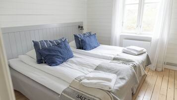 A double bed with two pillows, a bedside table, and a window with curtains.