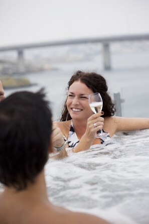 Una persona en un jacuzzi con un puente al fondo.
