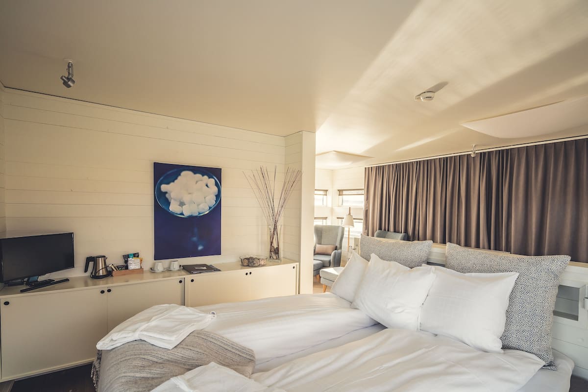 Habitación de hotel con cama, escritorio con televisor, cafetera y un cuadro en la pared.