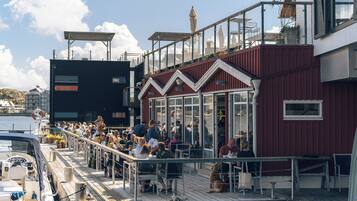A waterfront restaurant with outdoor seating, a deck, and a view of the water.