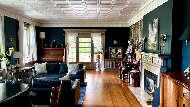 A spacious room with a large window, a piano, a fireplace, and a collection of framed artworks. - Clonmel Castle (Norfolk County)