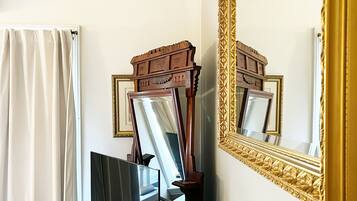 Une pièce avec un grand miroir, une commode en bois, un téléviseur et un canapé blanc.