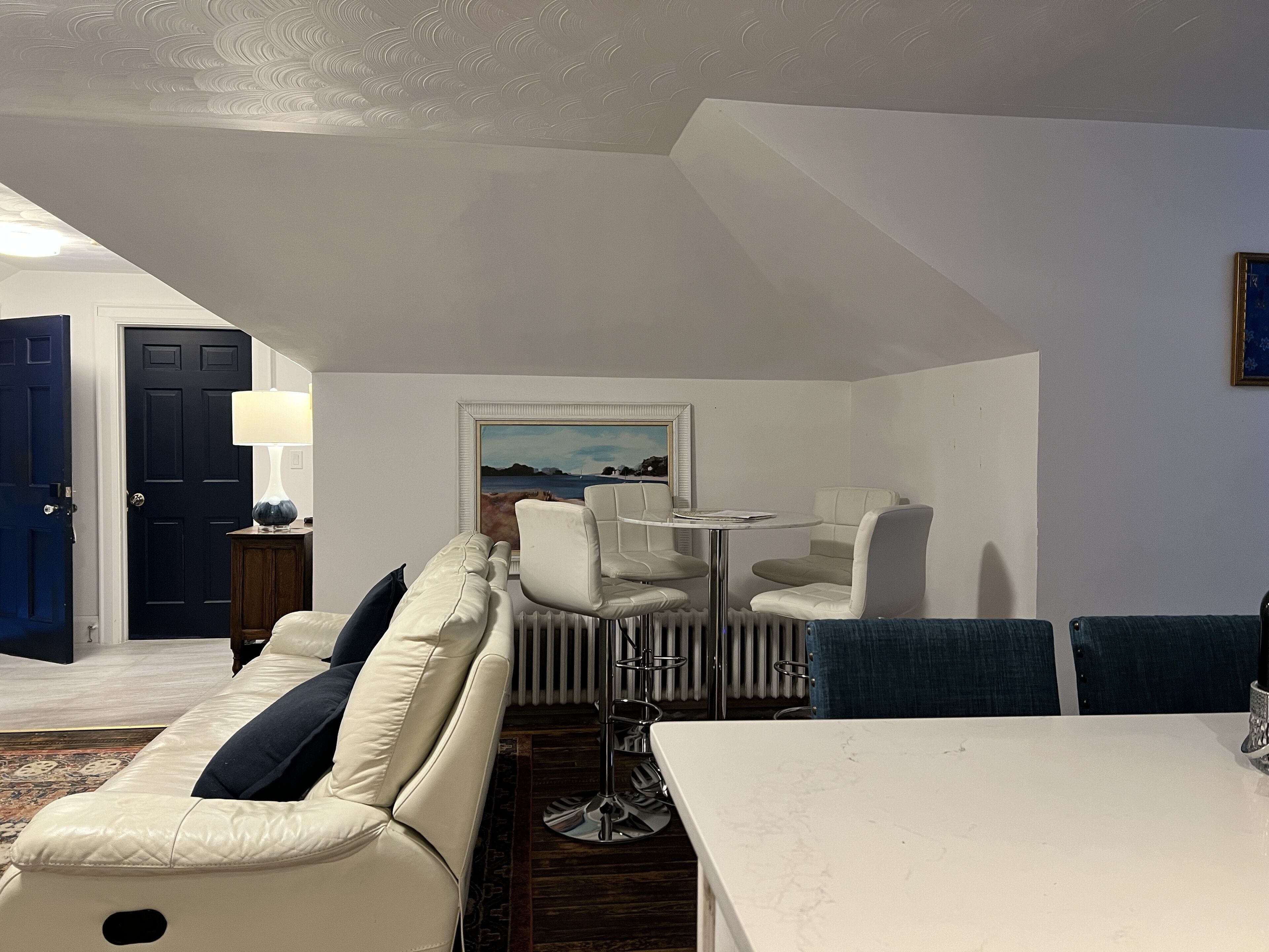 Una sala de estar moderna con un sofá, sillas, una mesa y un cuadro en la pared.