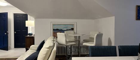Una sala de estar moderna con un sofá, sillas, una mesa y un cuadro en la pared.