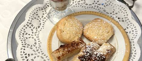 A dessert plate with a glass of layered dessert, cookies, and rolled pastries.