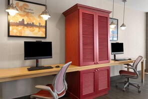 A workspace with two computer monitors, a red cabinet, and two office chairs. - Home2 Suites by Hilton Meridian (Meridian)