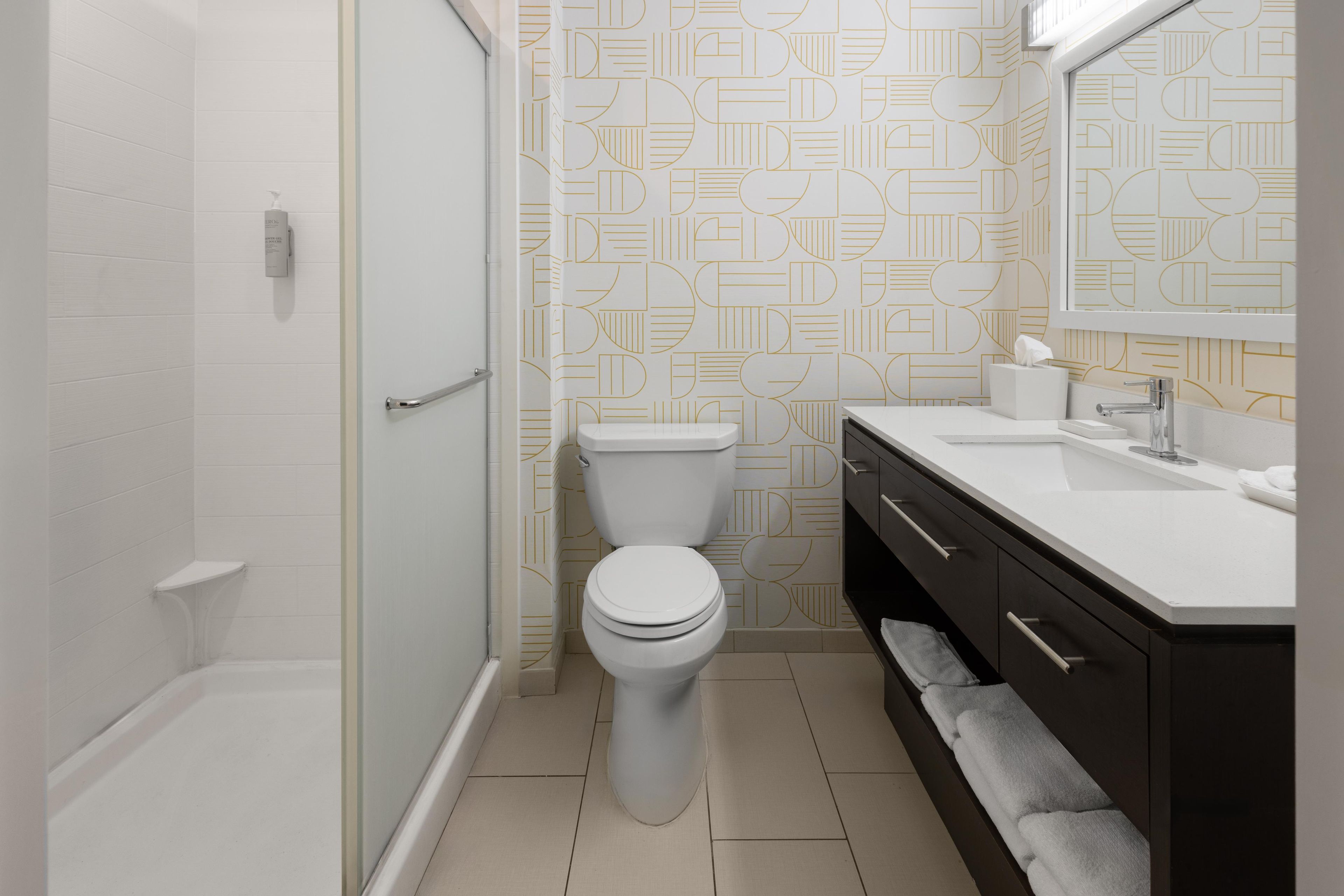 A modern bathroom with a shower, toilet, and vanity.