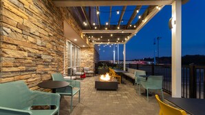 An outdoor patio with stone walls, a fire pit, and seating. - Home2 Suites by Hilton Meridian (Meridian)
