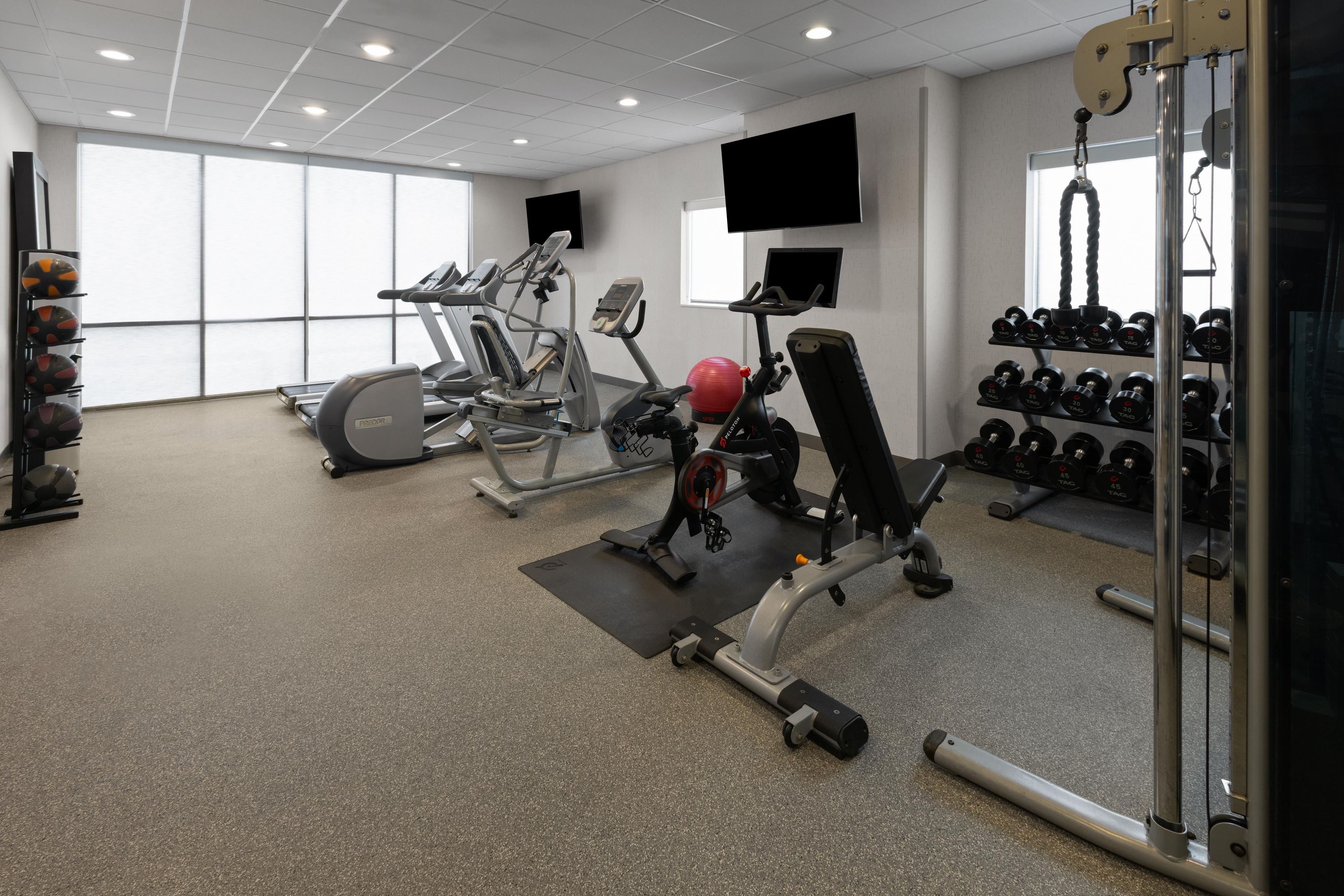 A gym with cardio machines, free weights, and a mirror.