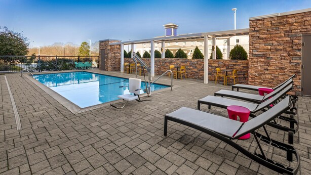 A rooftop pool area with lounge chairs, a pool, and a stone wall. - Home2 Suites by Hilton Meridian (Meridian)
