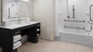 A modern bathroom with a double sink vanity, a shower with grab bars, and patterned wall tiles.