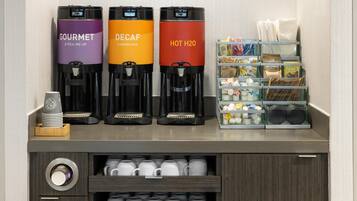 Een koffiehoek met drie dispensers, gelabeld 'GOURMET', 'DECAF' en 'HEET WATER'.