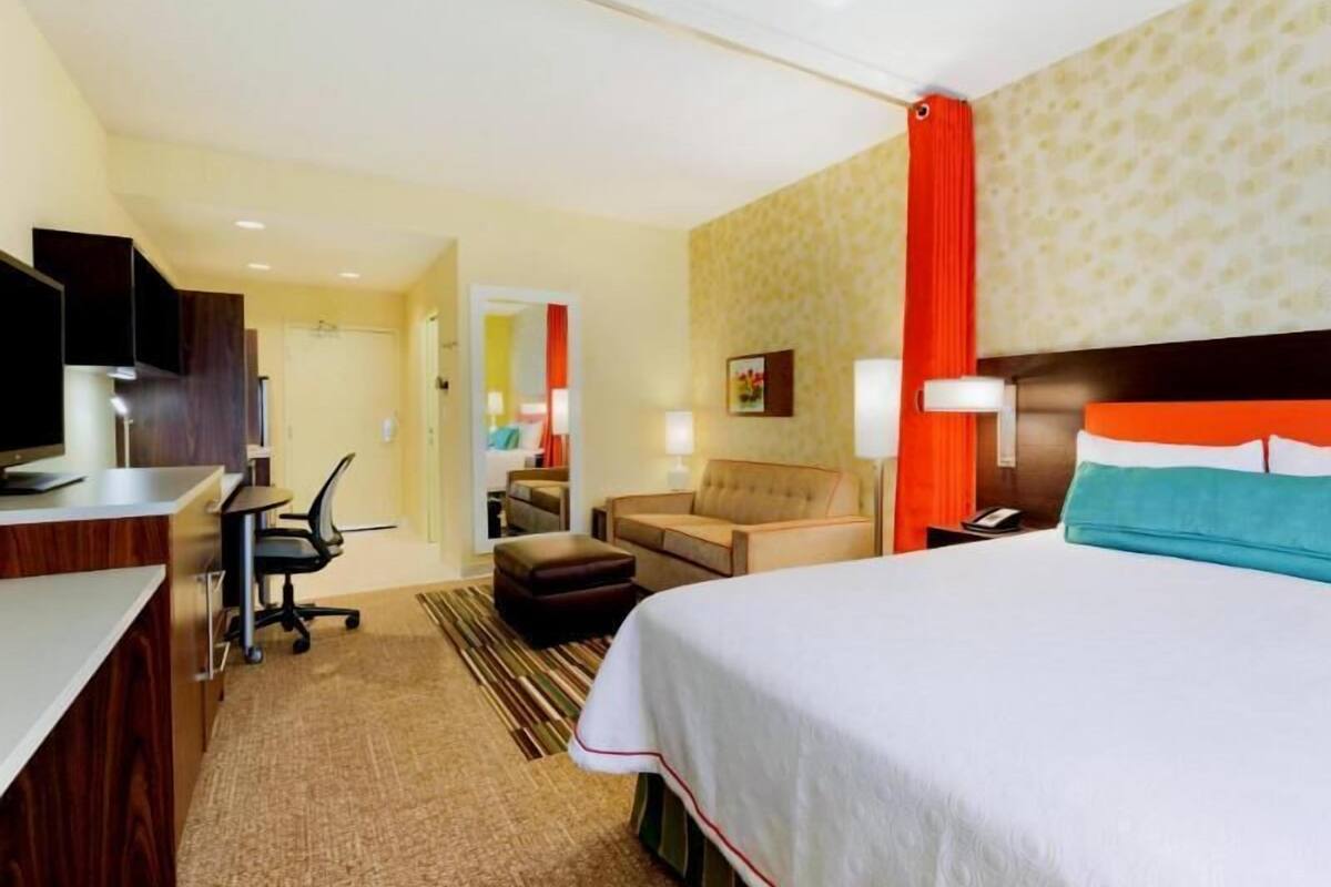Una habitación de hotel con una cama, un escritorio, una silla, un sofá y un televisor.