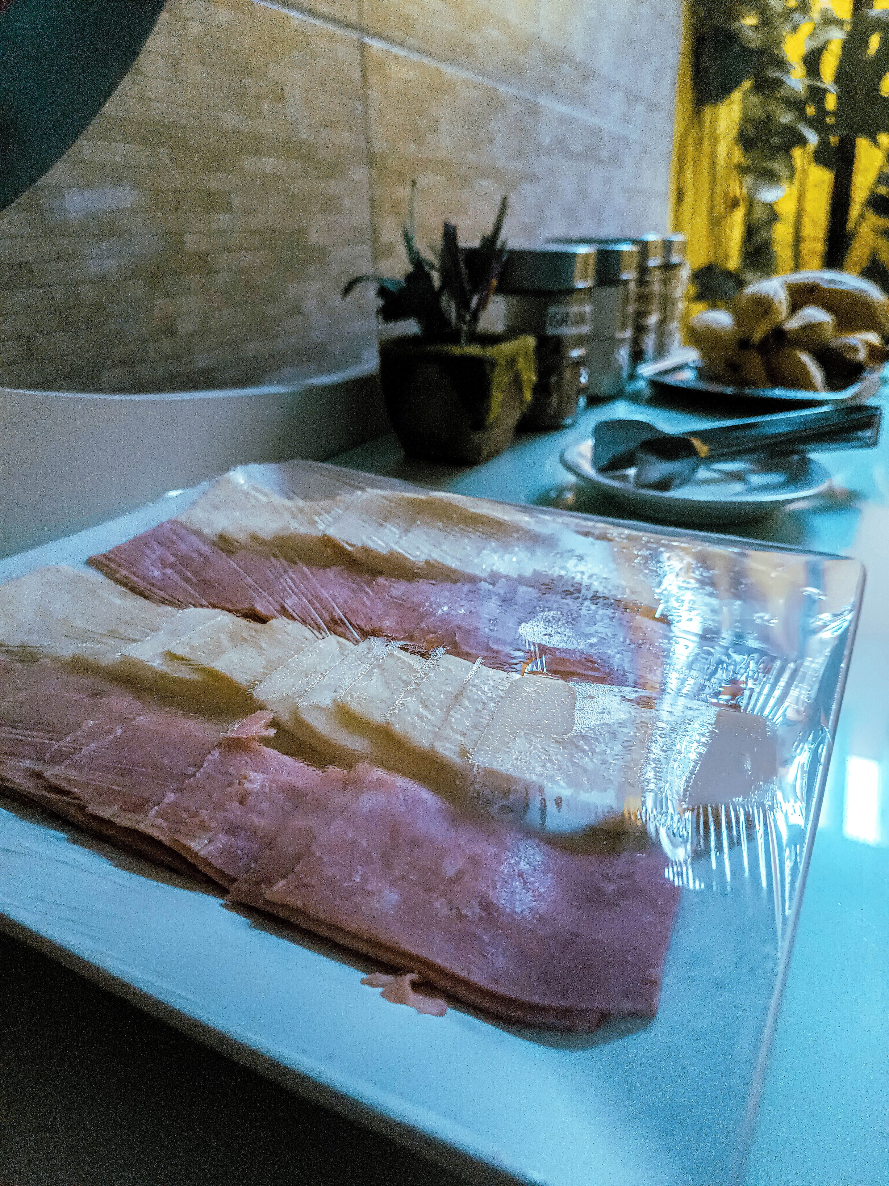 Una vitrina de vidrio muestra rebanadas de embutidos sobre una mesa.