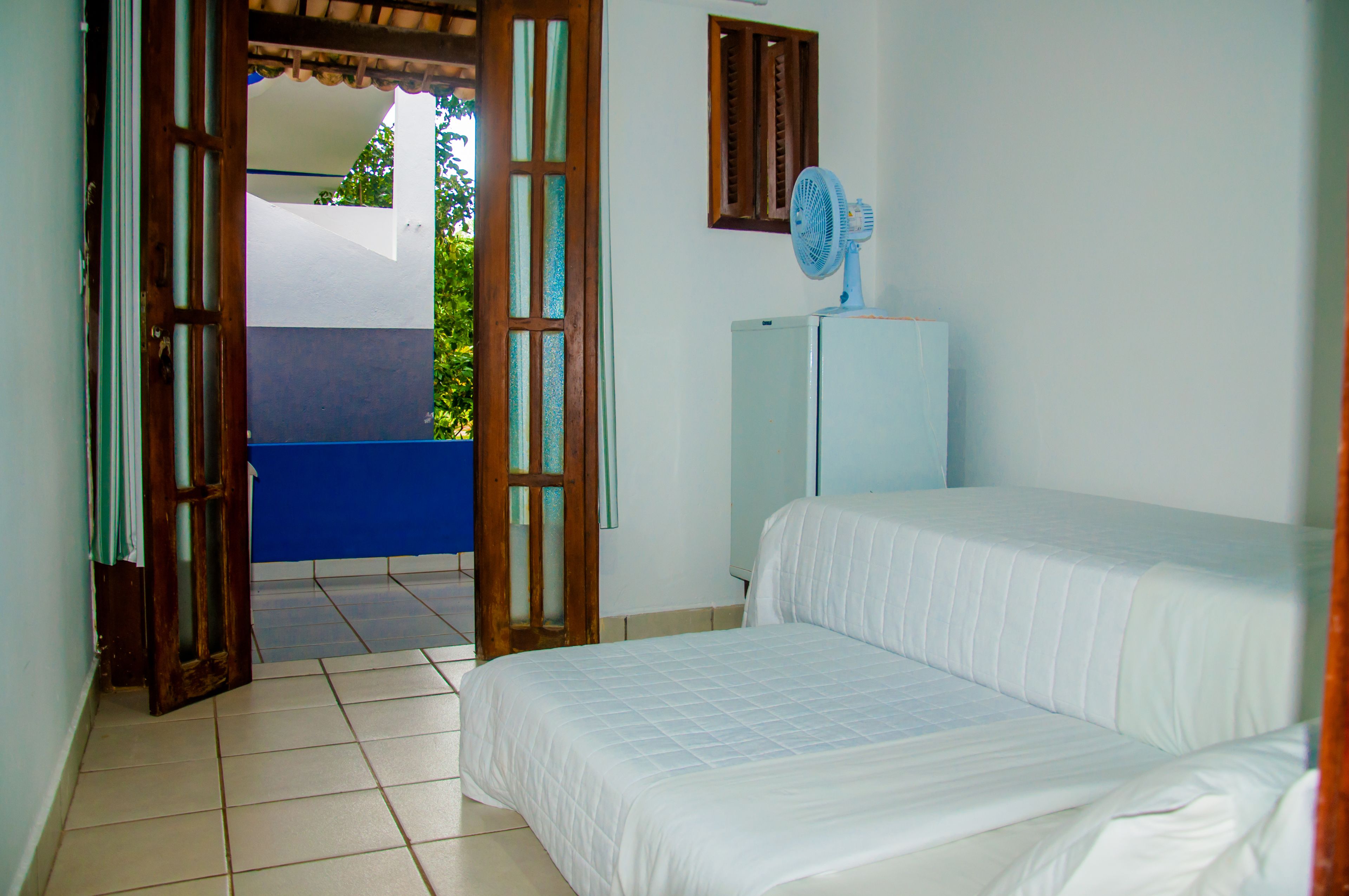 Un dormitorio con cama, ventilador y vista al exterior.