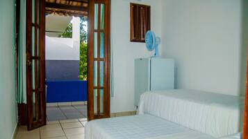 Un dormitorio con cama, ventilador y vista al exterior.