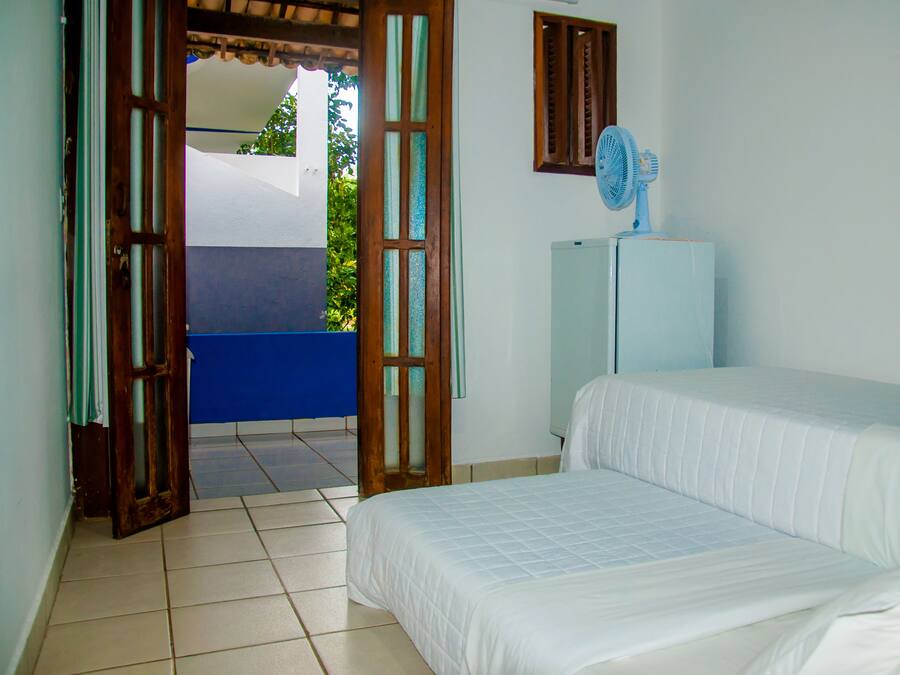 Un dormitorio con cama, ventilador y vista al exterior.