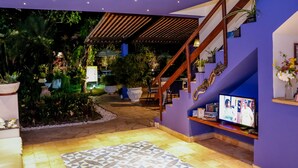 Un interior moderno con una escalera, un televisor y un área ajardinada.
