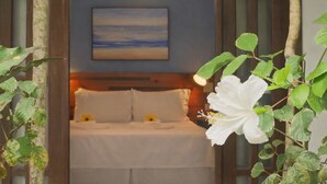 Un dormitorio con cama, almohadas, una mesita de noche, un cuadro colgado en la pared y una lámpara colgante.
