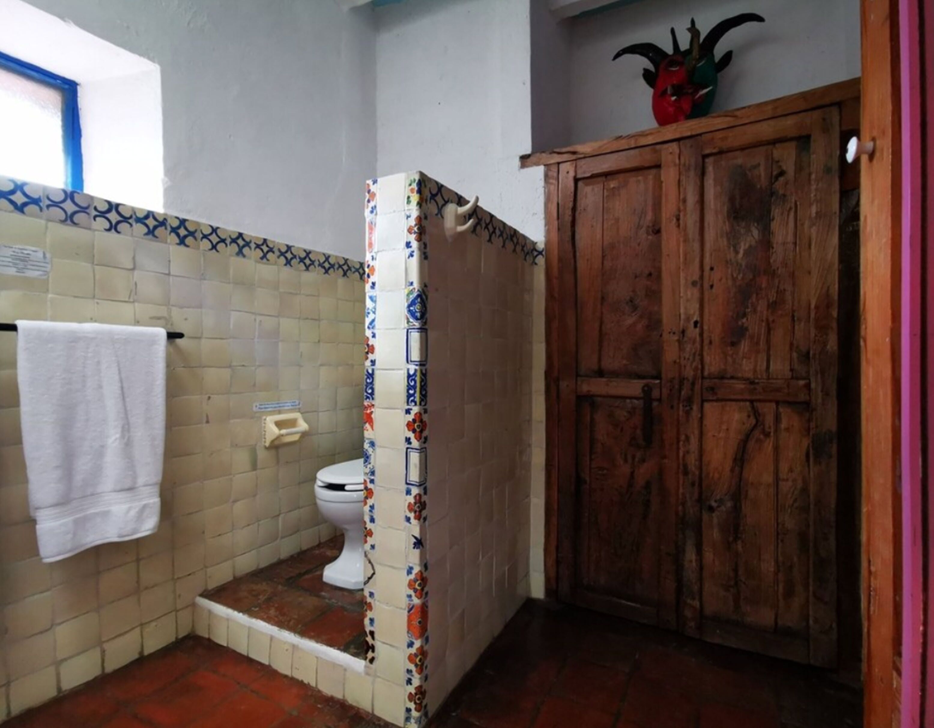 A bathroom with a toilet, a shower area, and a wooden cabinet.