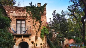 Un edificio rústico de piedra con un pequeño balcón y una entrada en arco.