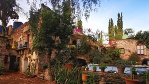 Un patio con muros de piedra, plantas en macetas y un camino de ladrillo.