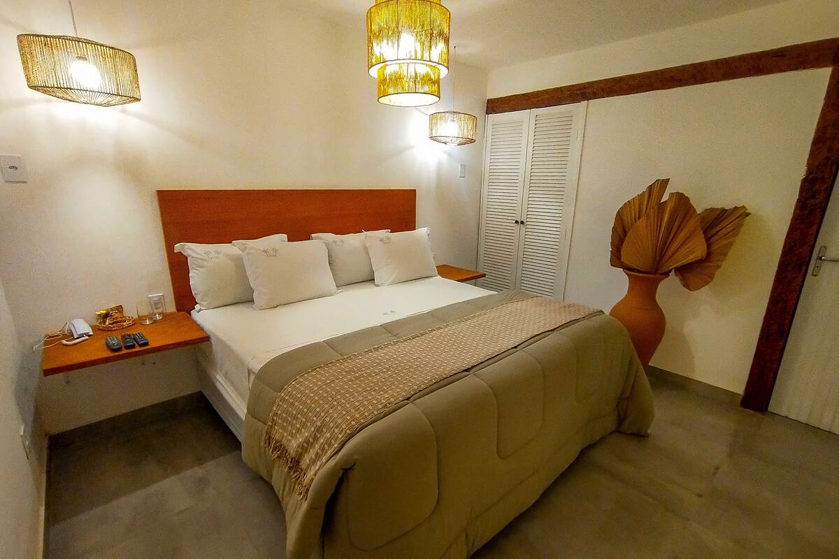 Un dormitorio con cama, mesitas de noche, lámpara y armario.