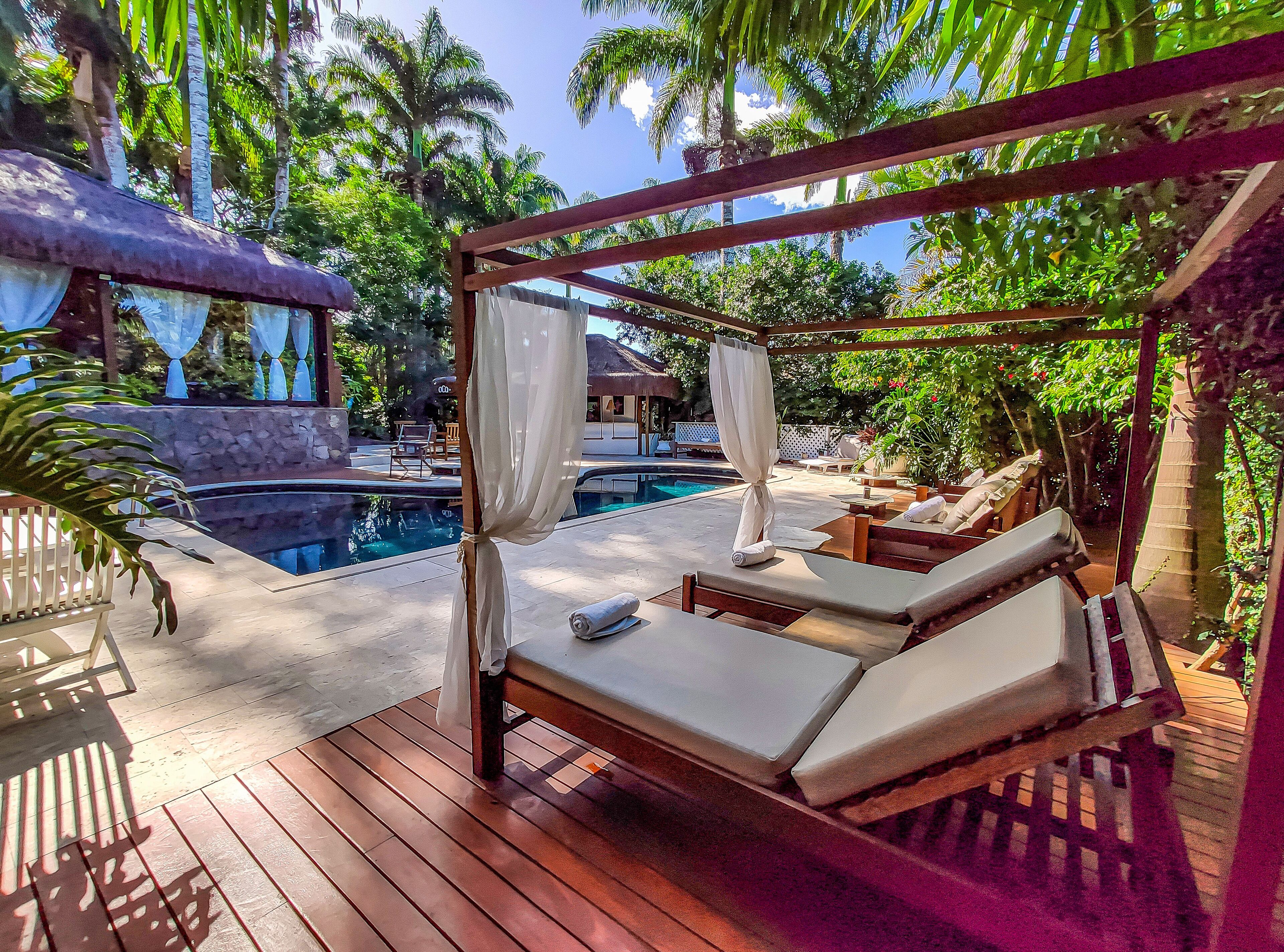 Una piscina al aire libre, sombrillas, sillones reclinables de piscina