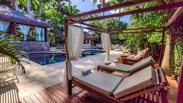 Una piscina al aire libre, sombrillas, sillones reclinables de piscina