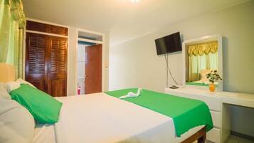 A hotel room with a bed, a desk, a television, and a mirror.