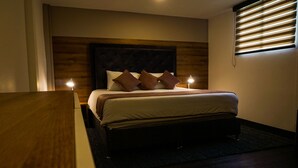 Ein Hotelzimmer mit einem hölzernen Kopfteil, einem Bett mit weißen Bettwäsche und braunen Kissen, zwei Nachttischlampen und einem Nachttisch aus Holz.