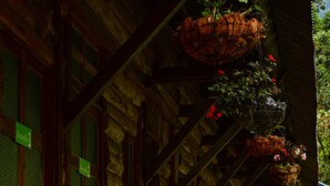 Ein rustikales Holzgebäude mit überdachter Veranda, Steinstufen und hängenden Blumenkörben.
