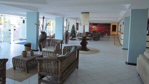 A spacious lobby with wicker furniture, a large vase, and a Christmas tree.