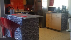 Een moderne keuken met een centraal eiland, roestvrijstalen apparatuur en rode accenten.