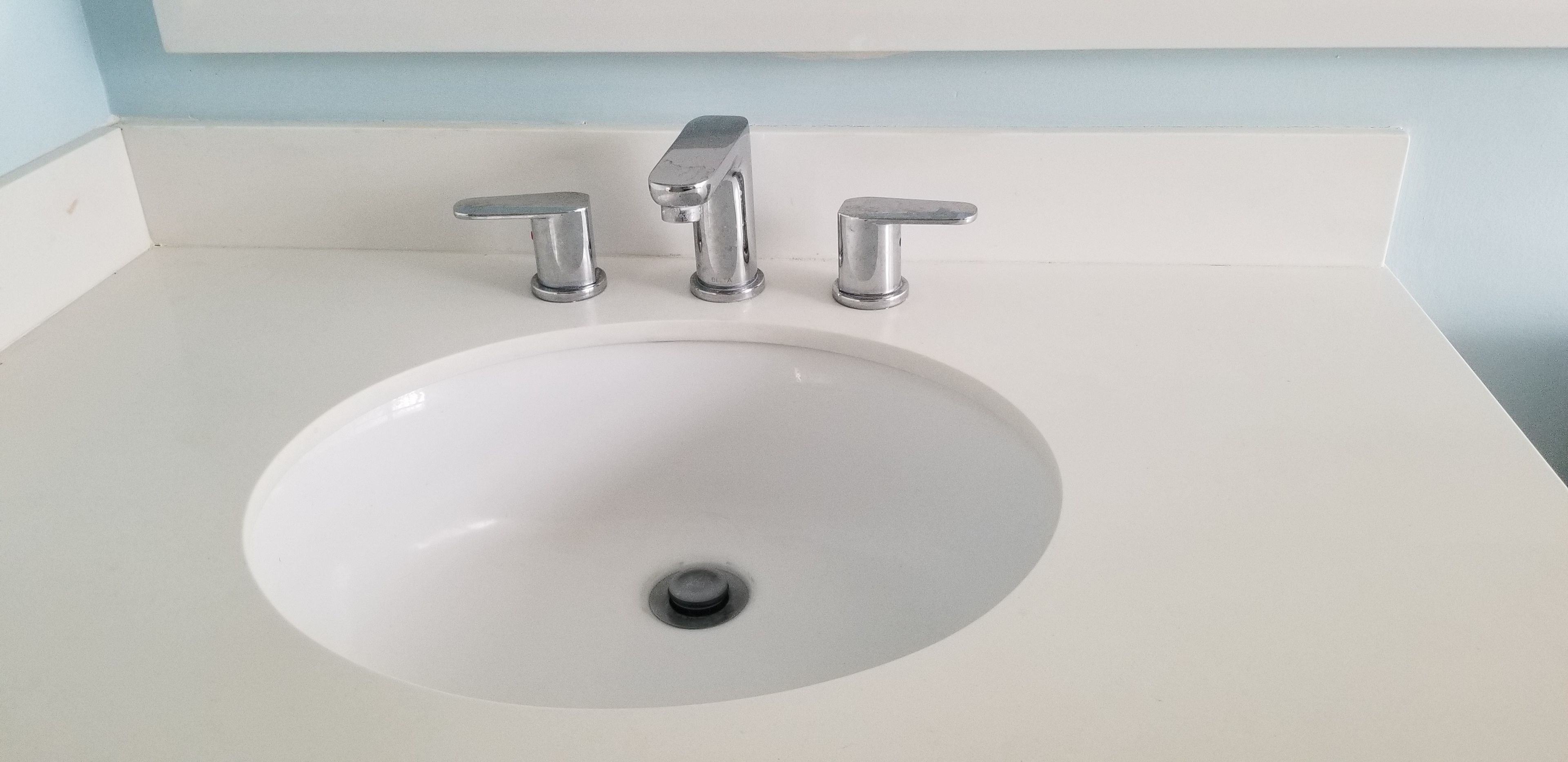 A white bathroom sink with a single faucet and a drain.
