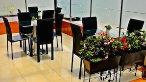 A restaurant with black chairs and tables, potted plants, and a view through a glass partition. - Hotel Casa Lamay (Bogotá)