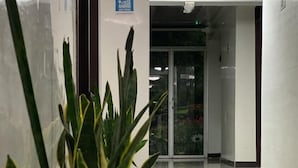 A hallway with a potted plant, a glass door, and a sign on the wall. - Hotel Casa Lamay (Bogotá)