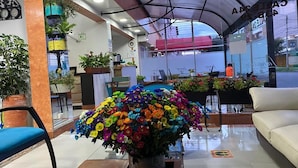 A lobby with a large floral arrangement, a clock, and a seating area. - Hotel Casa Lamay (Bogotá)