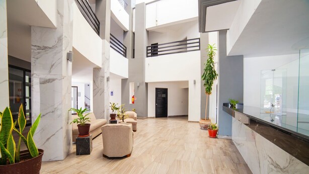 A spacious lobby with a high ceiling, marble flooring, and multiple seating areas.