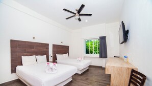 A hotel room with two beds, a desk, a chair, a ceiling fan, and a window with curtains.