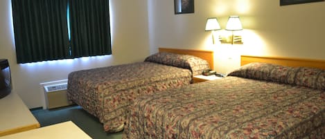 Quarto de hotel com duas camas, uma mesa e janela com cortinas.