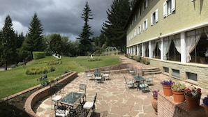 Eine Terrasse mit Gartenmöbeln, Steinboden und Blumentöpfen.